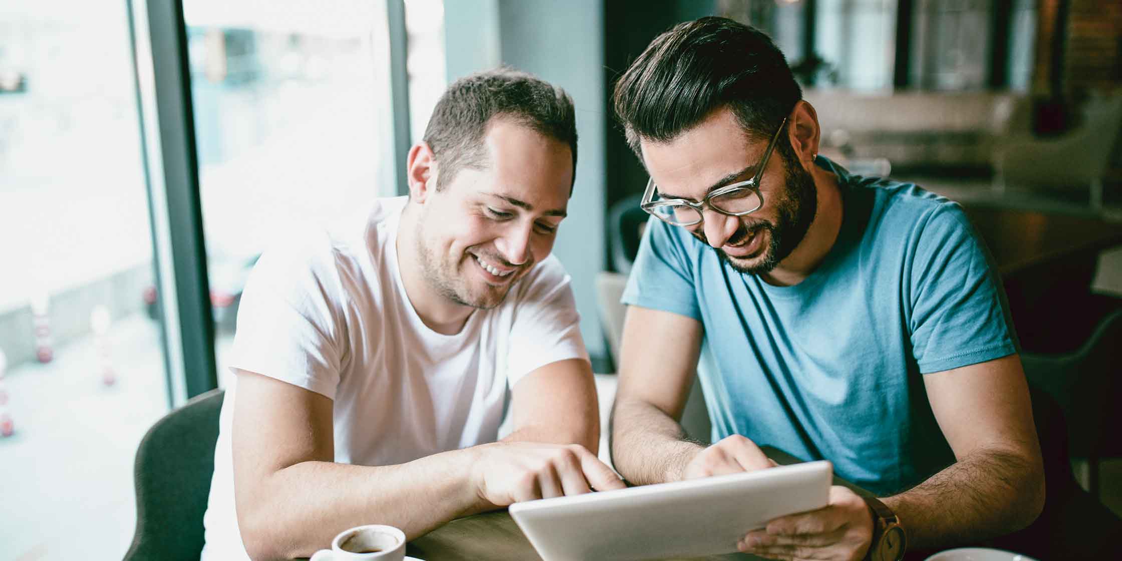 Two people using a tablet together at a café table.
