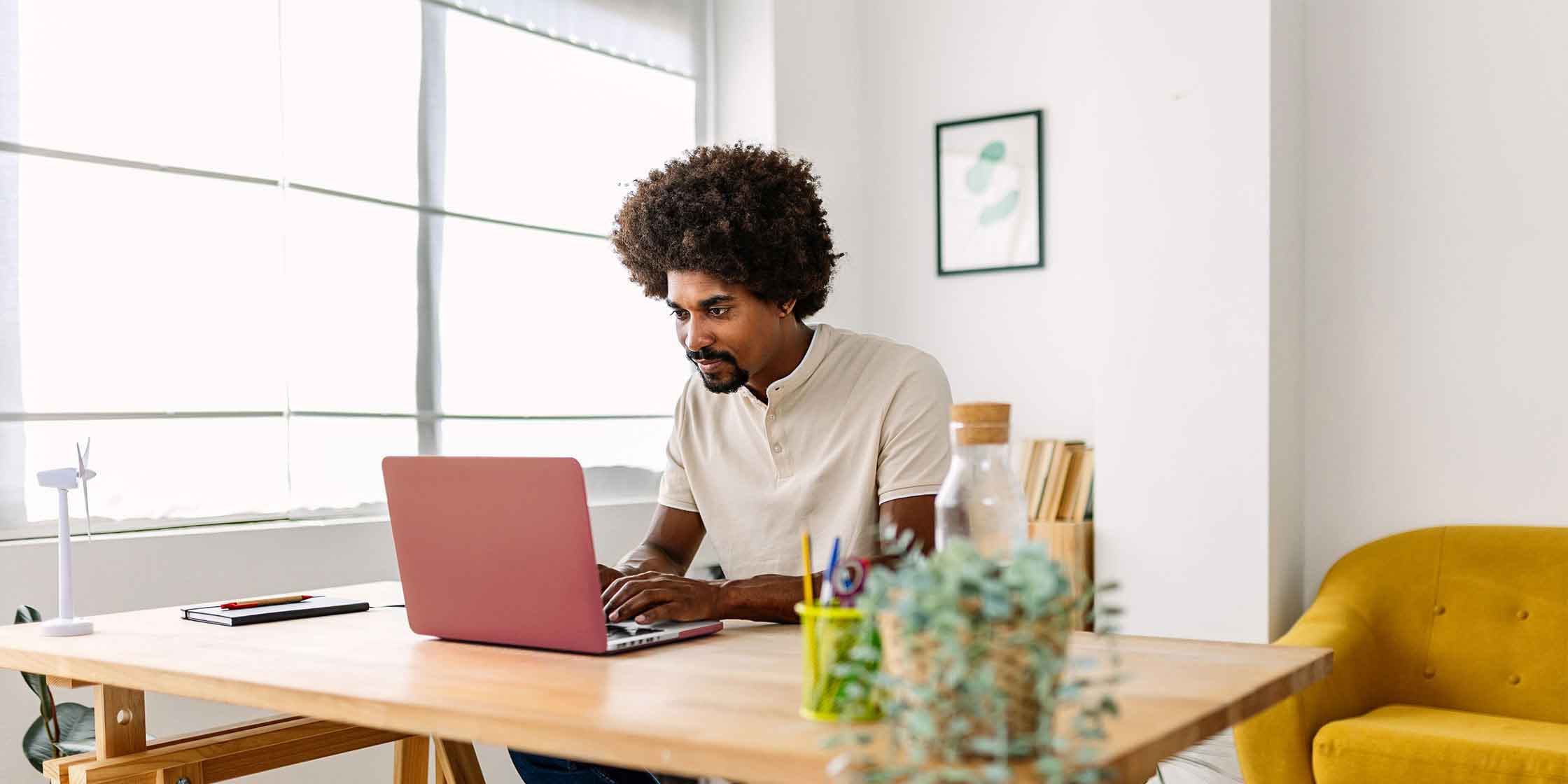 A person sits at a desk and looks at a laptop for information about how many lines of credit to have.