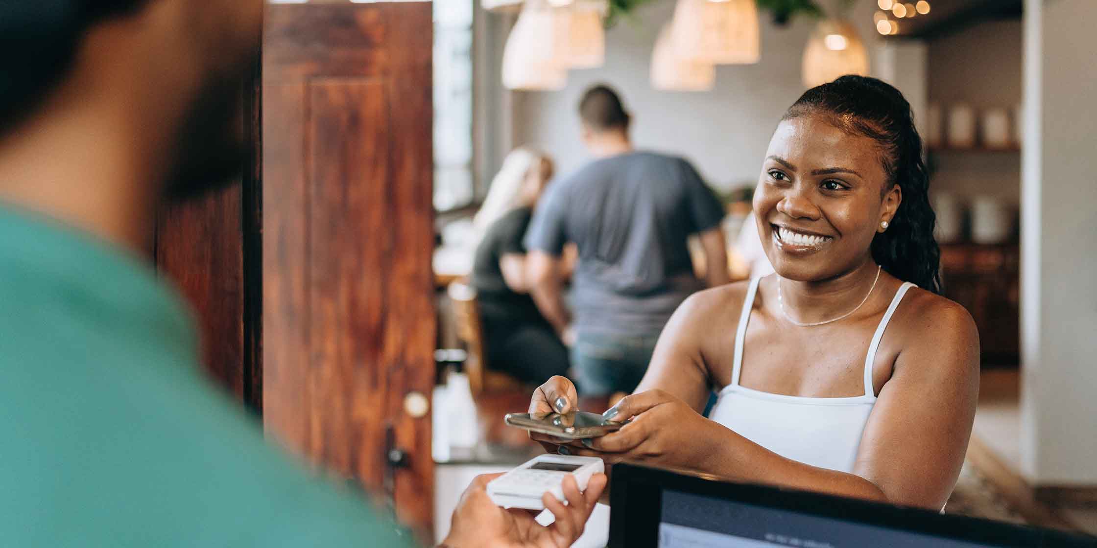 A person using their mobile wallet to make a contactless credit card payment at a restaurant.