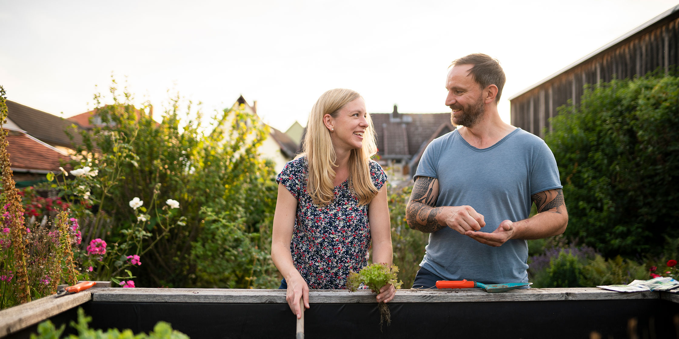 A smiling couple chatting while standing in their garden.