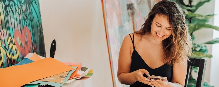 A photo of a small-business employee who’s smiling while reading on their phone about a SIMPLE IRA plan.