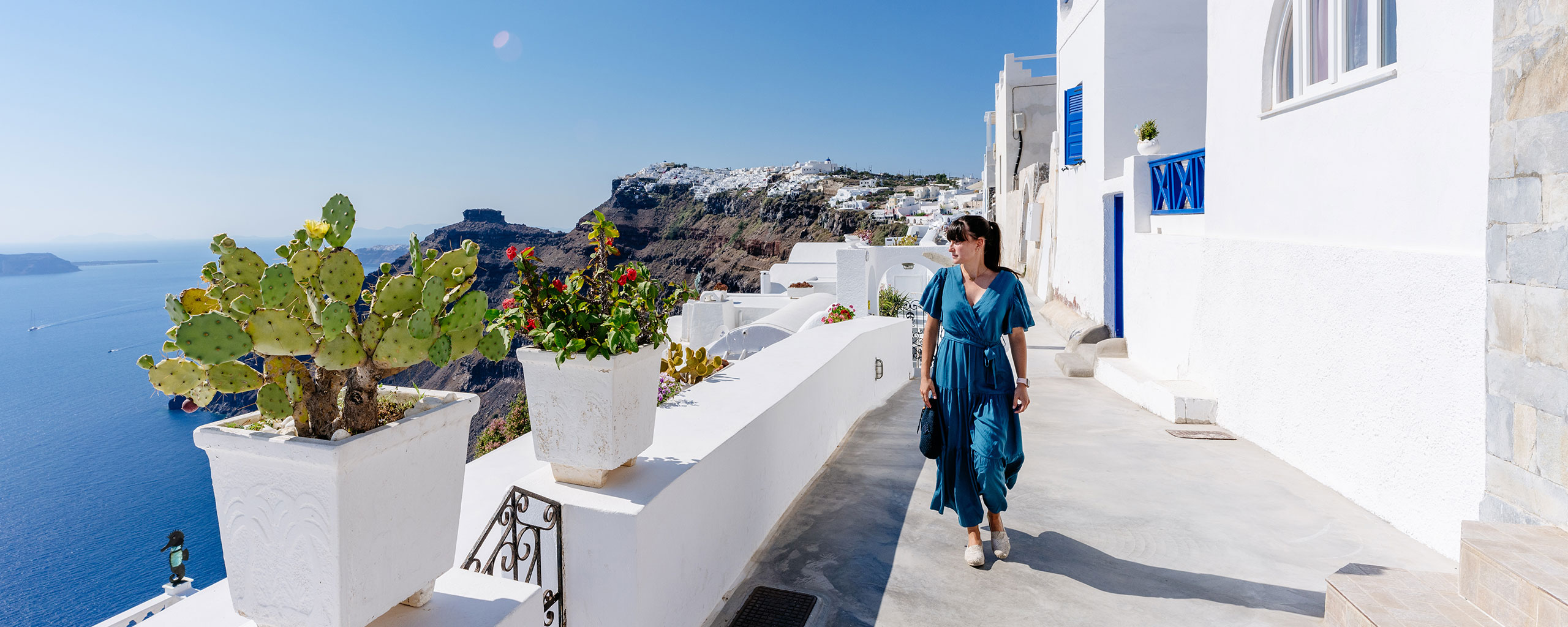 A photo of a young traveler strolling the Greek island of Santorini on a sunny day.