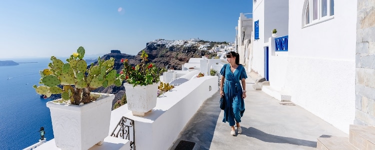A photo of a young traveler strolling the Greek island of Santorini on a sunny day.