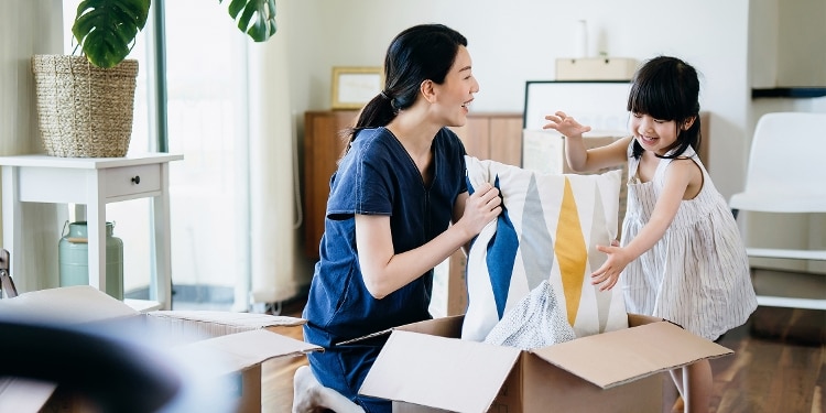A parent and child unpack a box of pillows together.