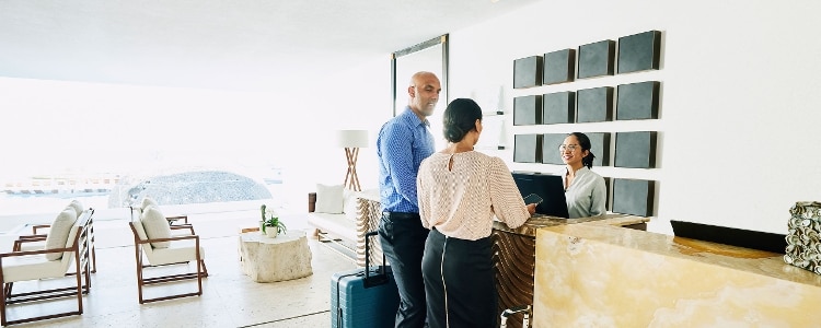 Two business travelers check in at a hotel reception desk.