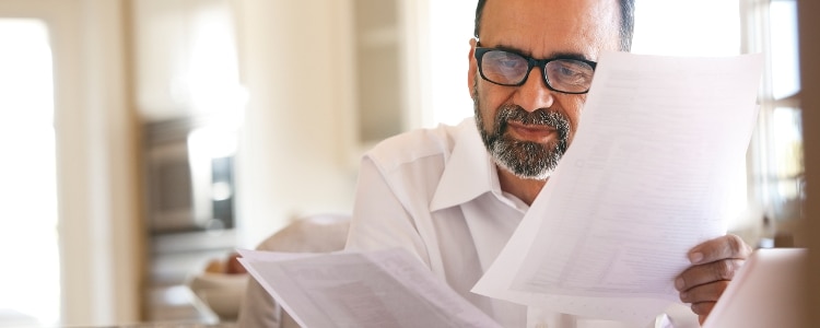 A person reads over bills that detail how much he owes in revolving debt and installment debt.