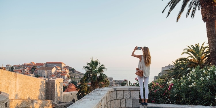 A person stands at an overlook and takes a photo of the view.