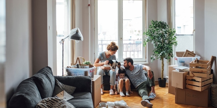 Two parents, a child and a dog surrounded by boxes in their new apartment.