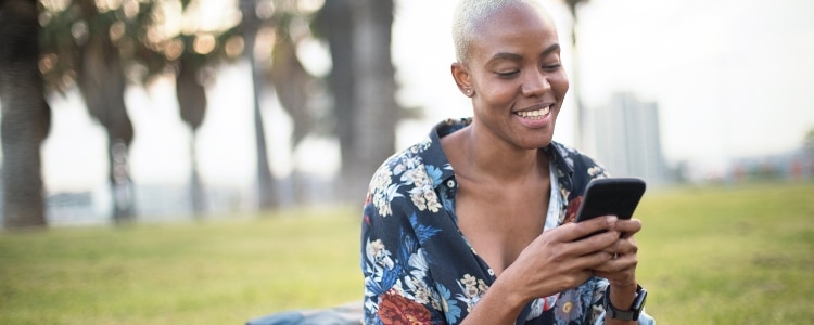 A person in a park checks their credit score from their phone.
