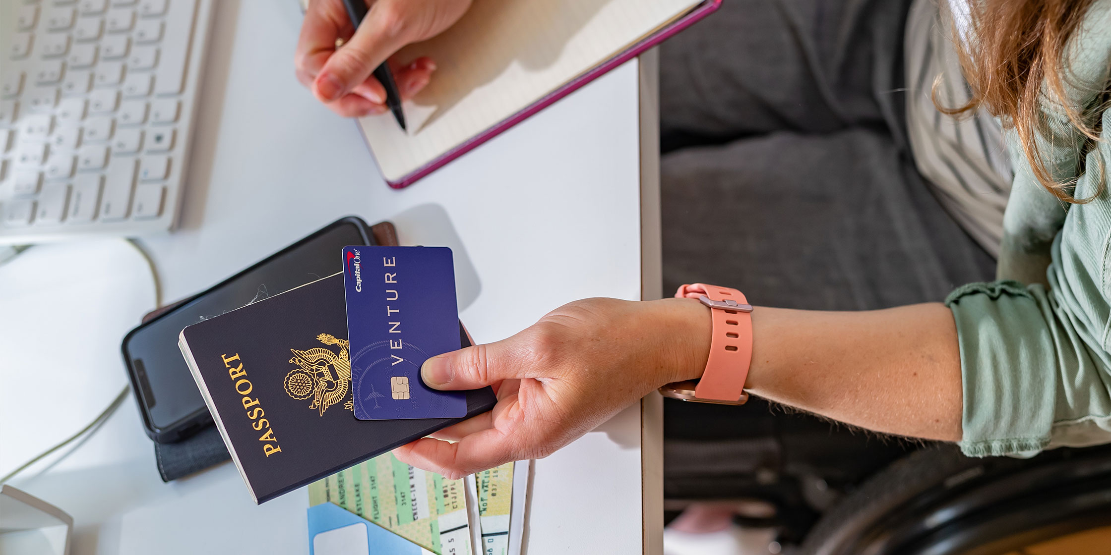 A close-up of a person’s hand holding a passport and a Capital One Venture card.