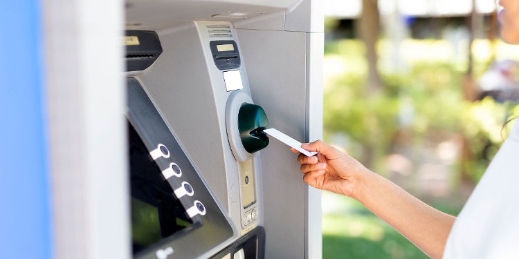 A person inserts a card in an ATM terminal.