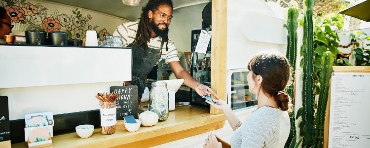A person uses their secured credit card to pay for coffee at a food truck.
