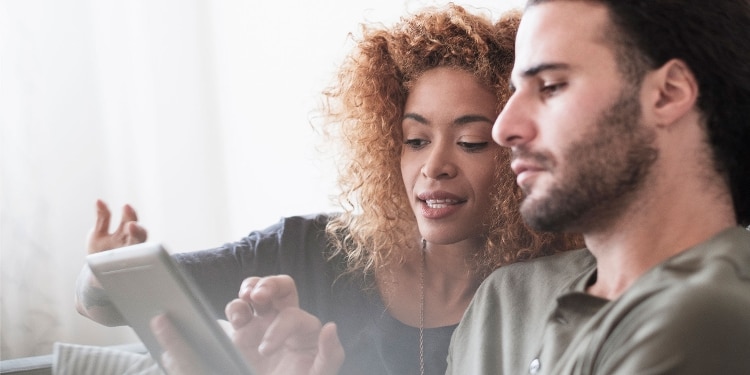 Two people looking at a tablet consider the prime rate and how it affects them.