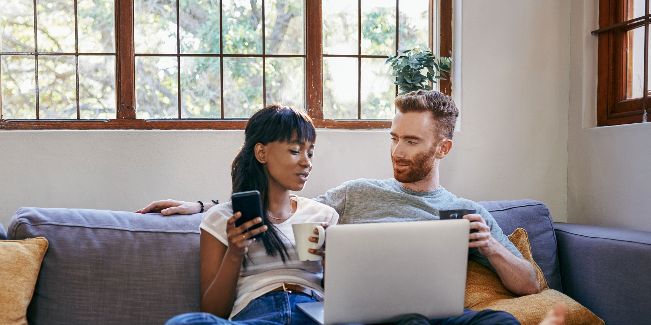 Two people use a laptop to learn about the differences between interest rates and APRs.