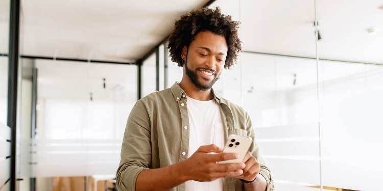 A person in a glass office looks at their phone screen.