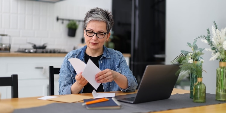 A person reviews credit card documents near a laptop.