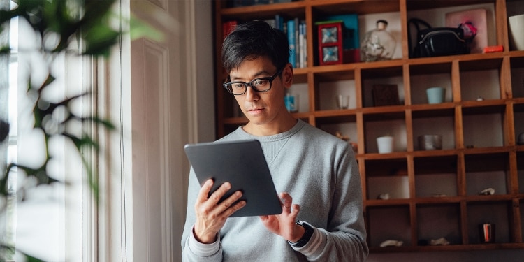 A person in glasses researching credit locks and credit freezes on a tablet.