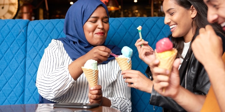 Three friends smiling and eating ice cream together.
