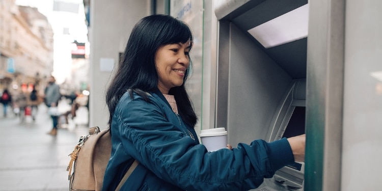 A person uses an ATM to get cash from their credit card.