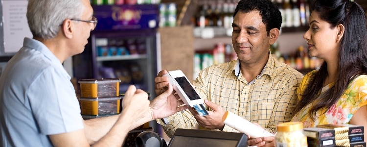 Store associate holds a credit card reader while a customer pays for their purchases.