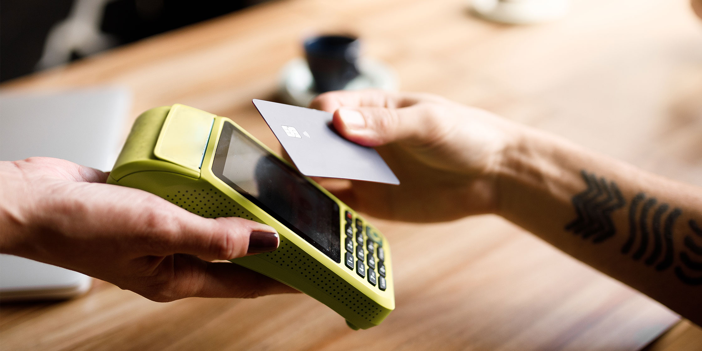 A person pays for an item by holding their credit card to a contactless reader.