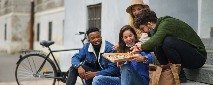 A group of friends enjoy a pizza they paid for with a credit card.