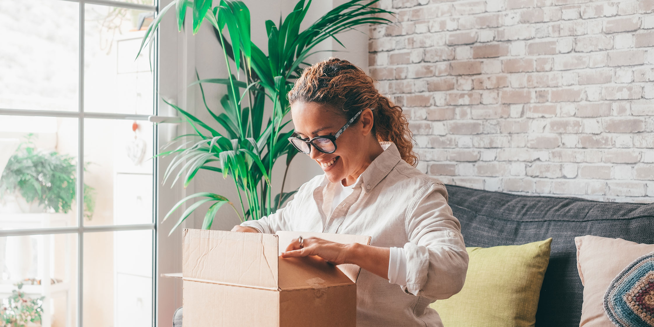 A person sitting on their couch and opening a package.