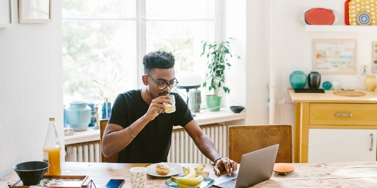 A person sits at a table and looks at a laptop for information about personal loans.