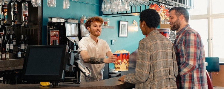 Two people use their debit card to enjoy popcorn and a movie.