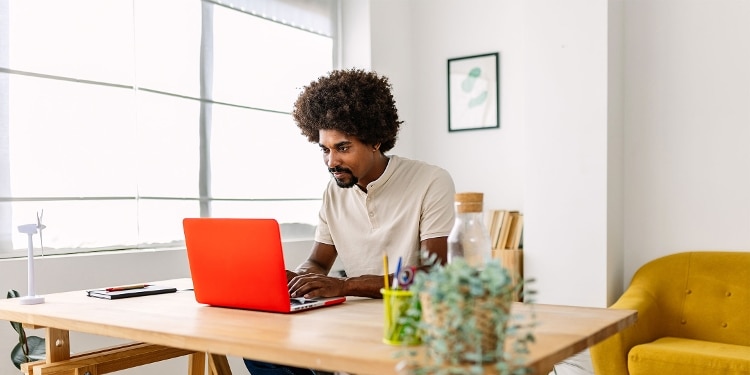 A person sits at a desk and looks on a laptop for information about how many lines of credit to have.