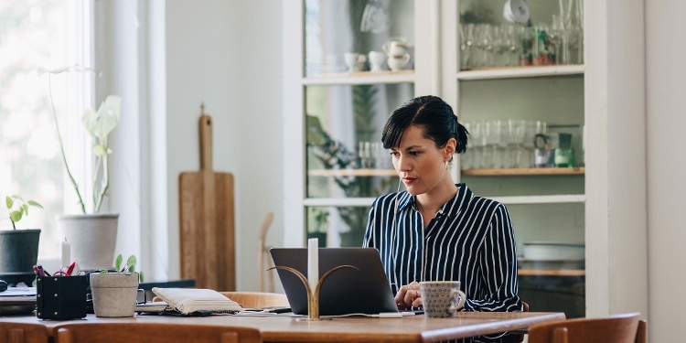 A person sits at a desk and looks at information on a laptop about a personal loan.