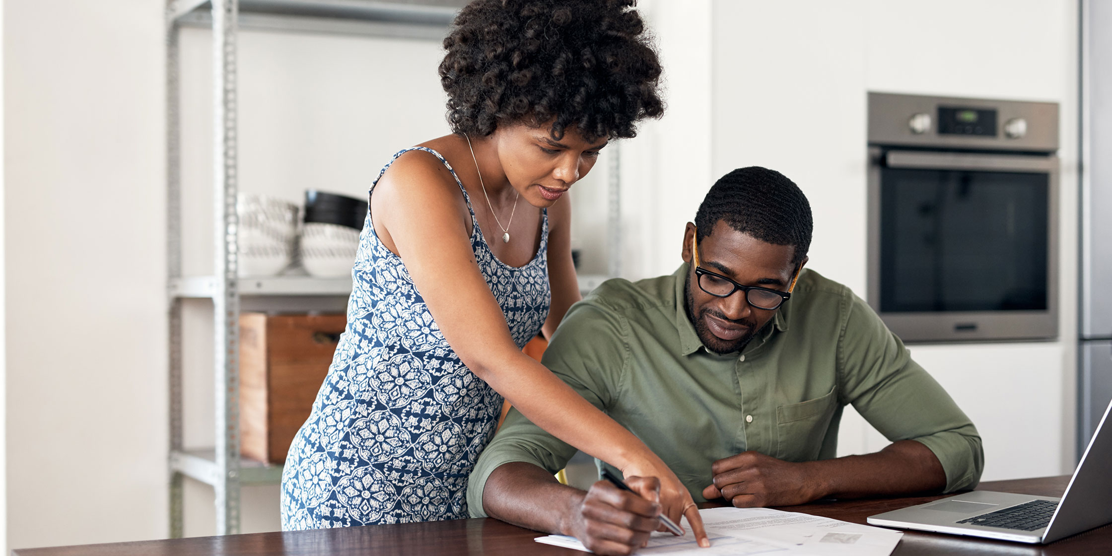 Two people point to and look at credit card terms on a table in front of them.