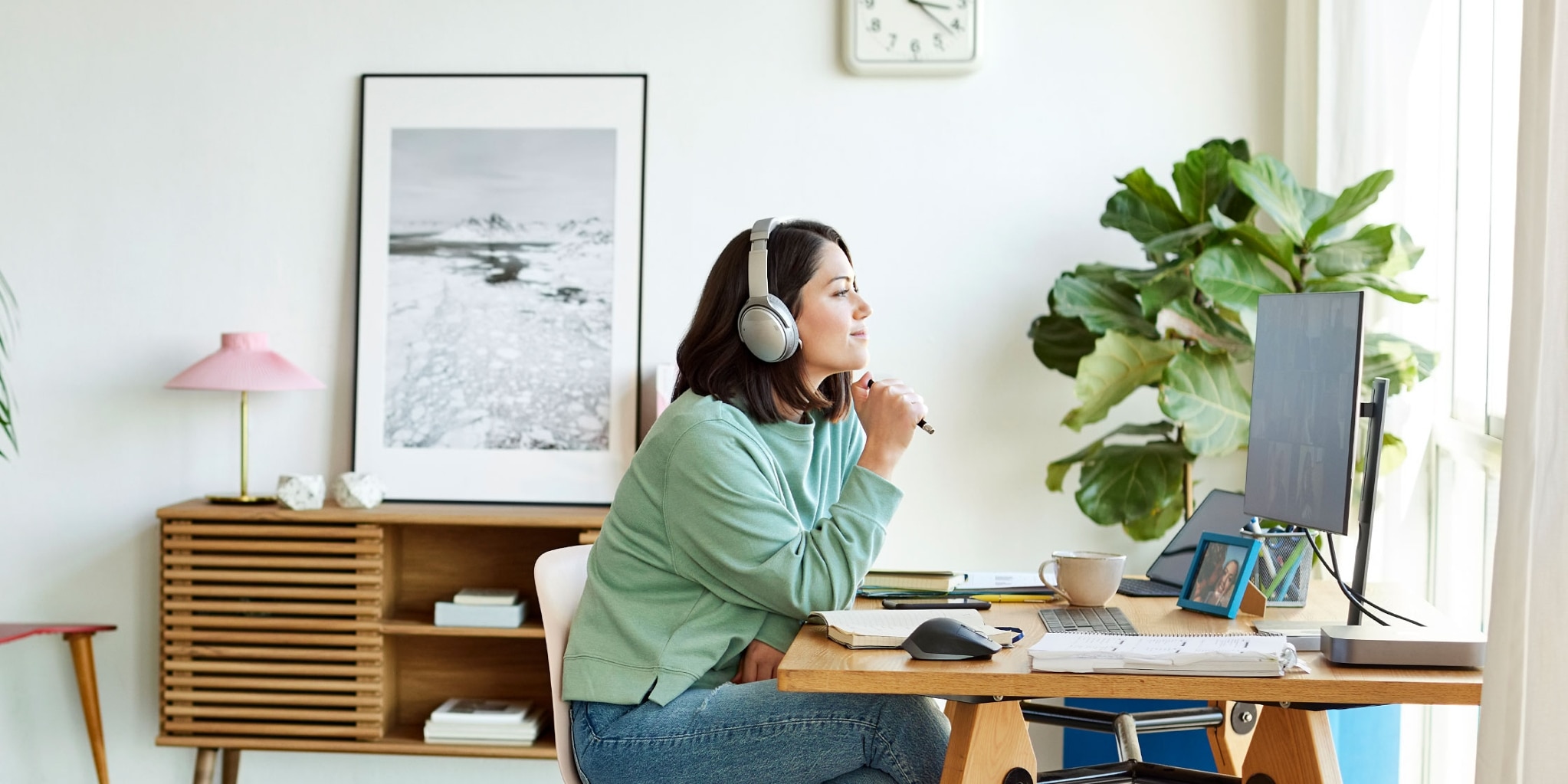 A person wearing headphones sits at a desk and reads on a computer screen about how much they need to make to file taxes.