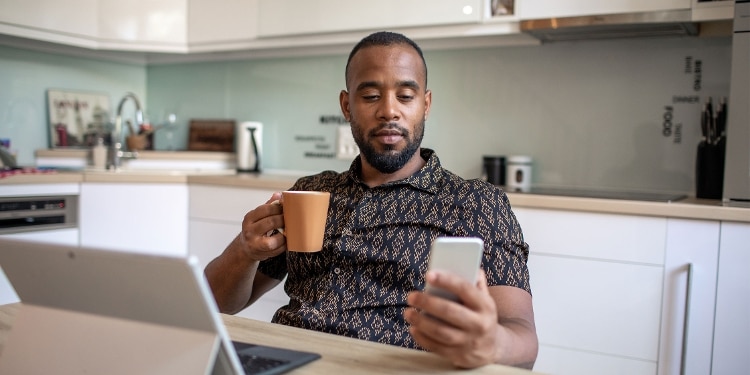 A person checks their phone to compare credit cards before applying.