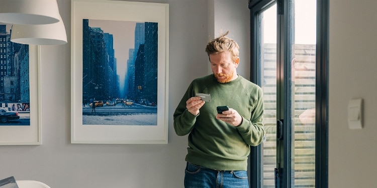 A person looks at their credit card and phone for credit card security tips.