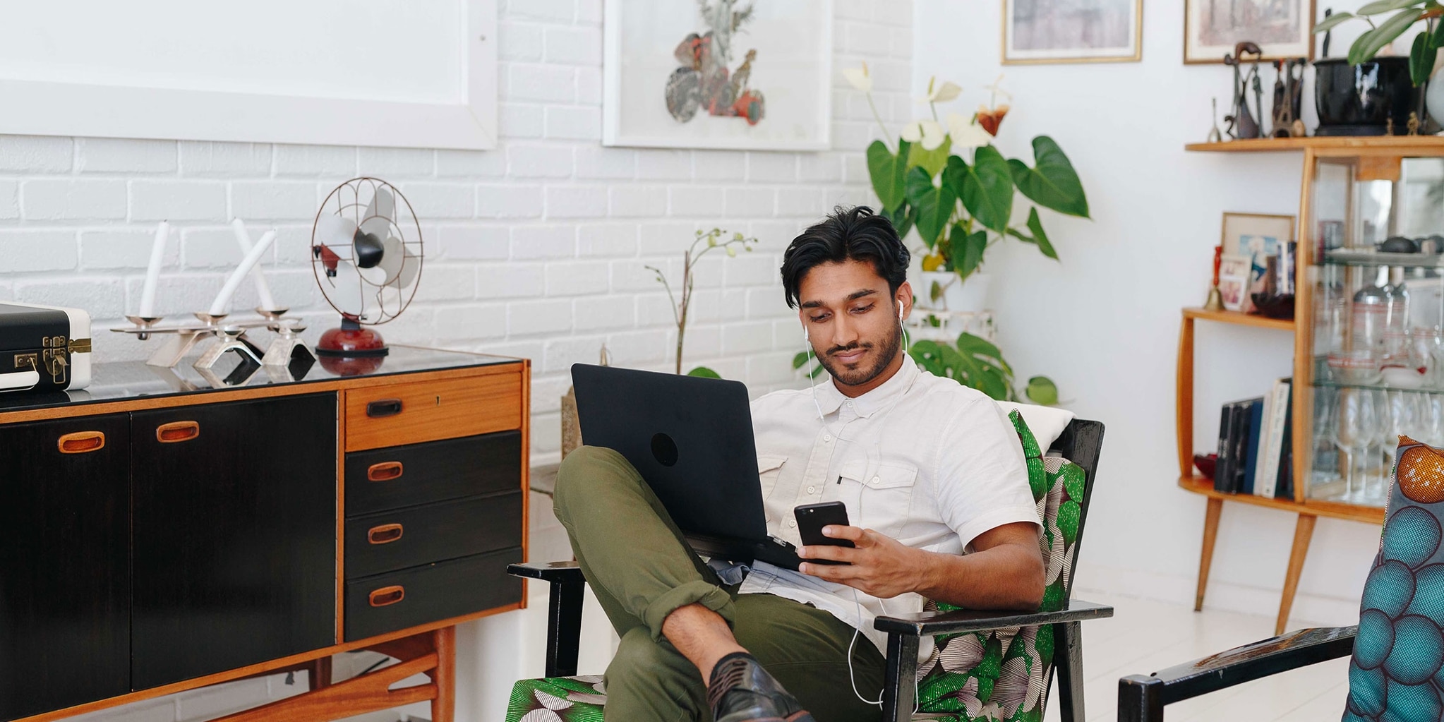 A young person with a mobile phone and a laptop checking how a hard credit check might affect their credit.