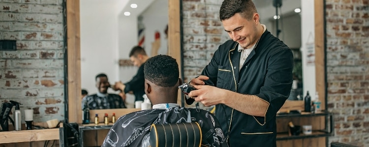 A barber gives a haircut to a customer in a barbershop.