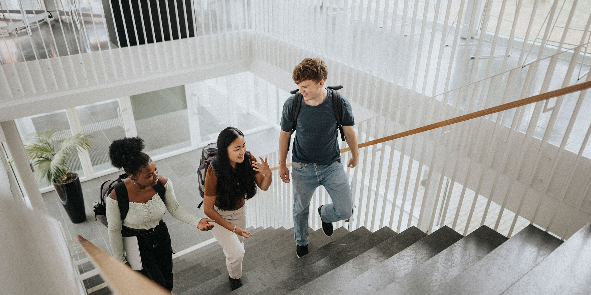 Three college students walk upstairs on campus together.