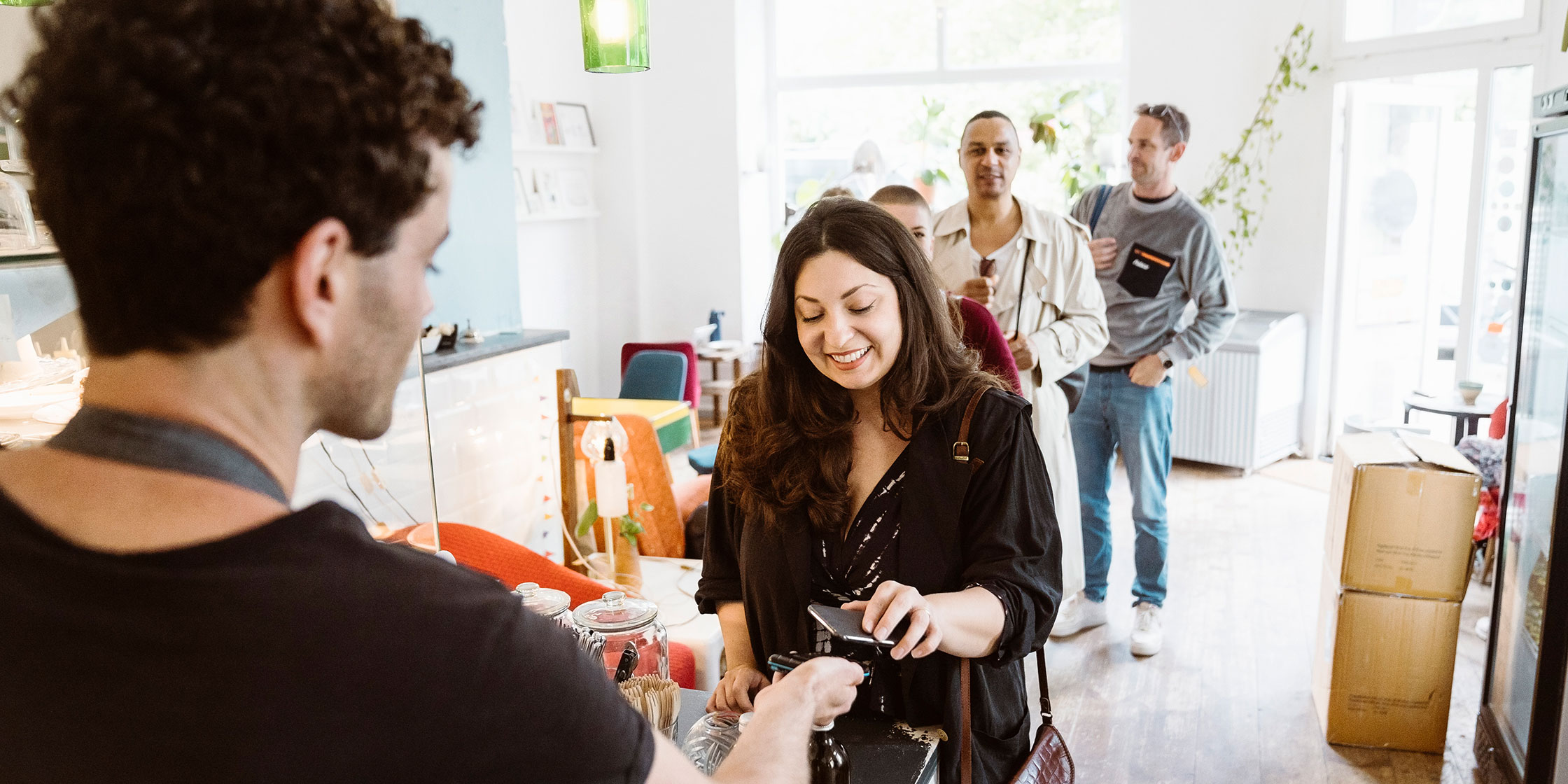 A woman taps her card at a store’s point-of-sale system.