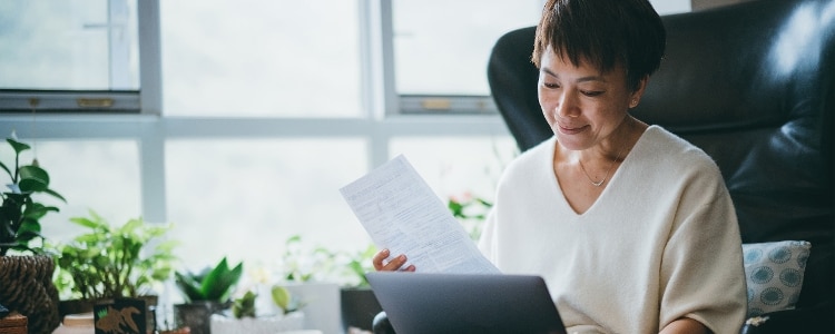 Person sitting reviews their pension plan on a tablet and a piece of paper.