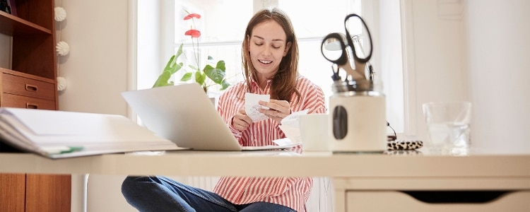 A person looks at a receipt while sitting at a desk.