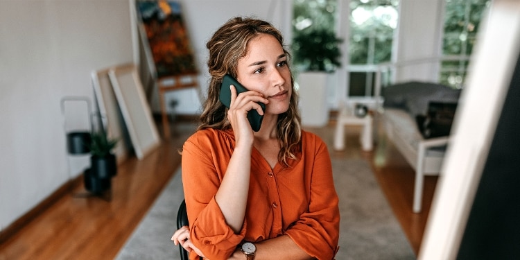 A person talking on the phone while sitting in a chair in their house.