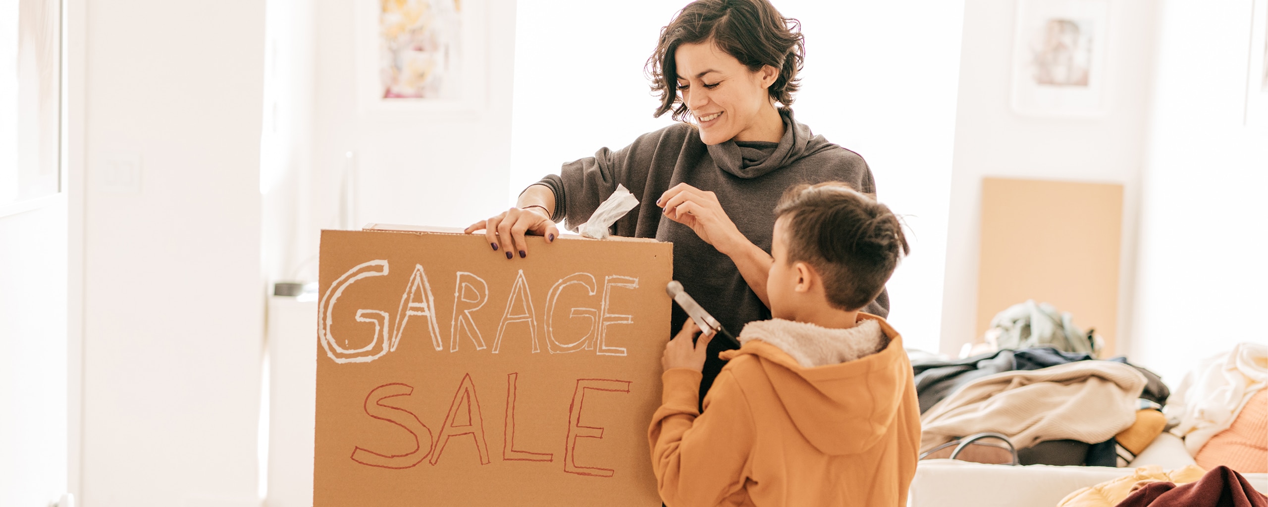 A parent and their child make a garage sale sign so they can build residual income.