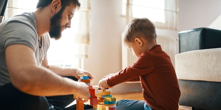 A bearded father playing with toys with his young son.