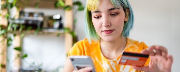 A person looks at their debit card and phone to report fraud.
