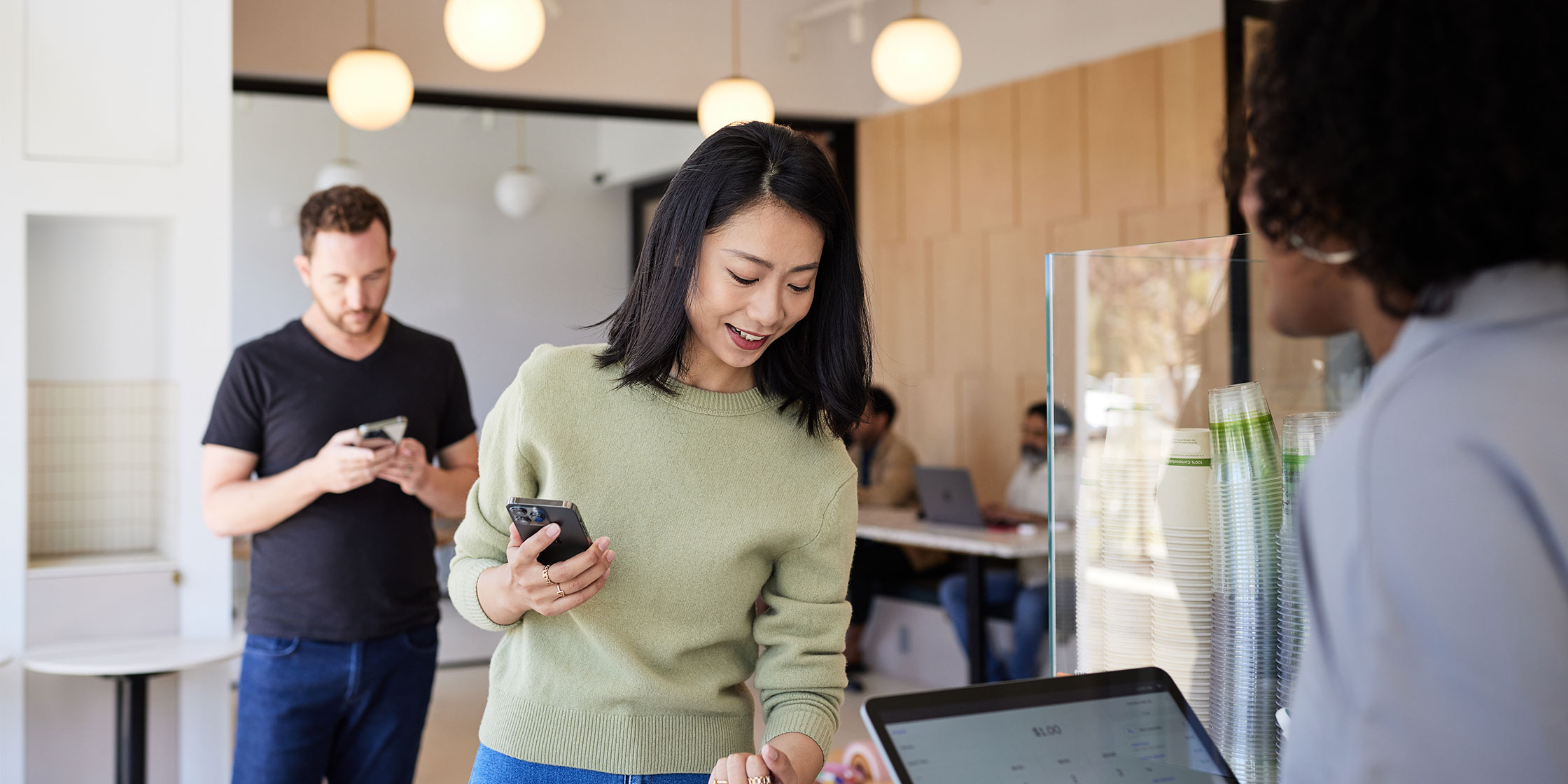 A smiling person paying at the register with their low-interest credit card.