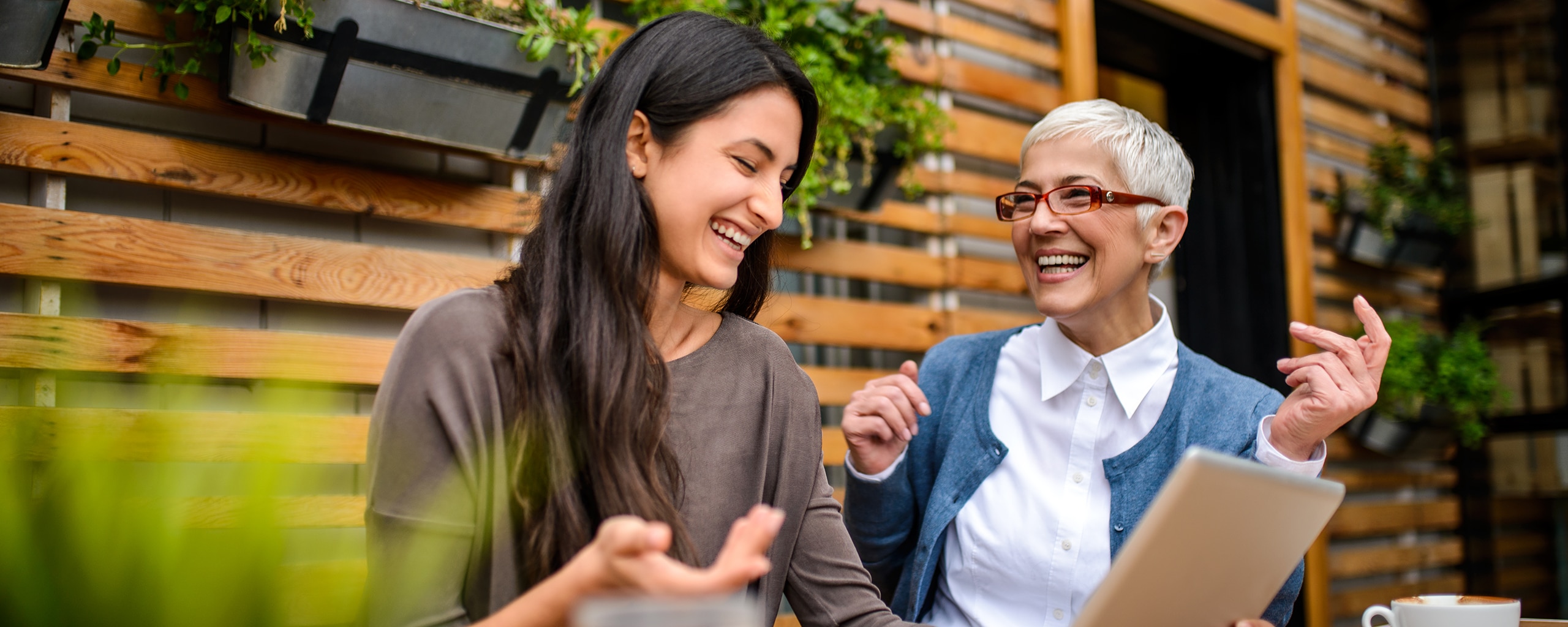 Two happy, smiling women using a digital tablet at the bar.