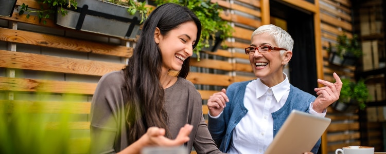 Two happy, smiling women using a digital tablet at the bar.
