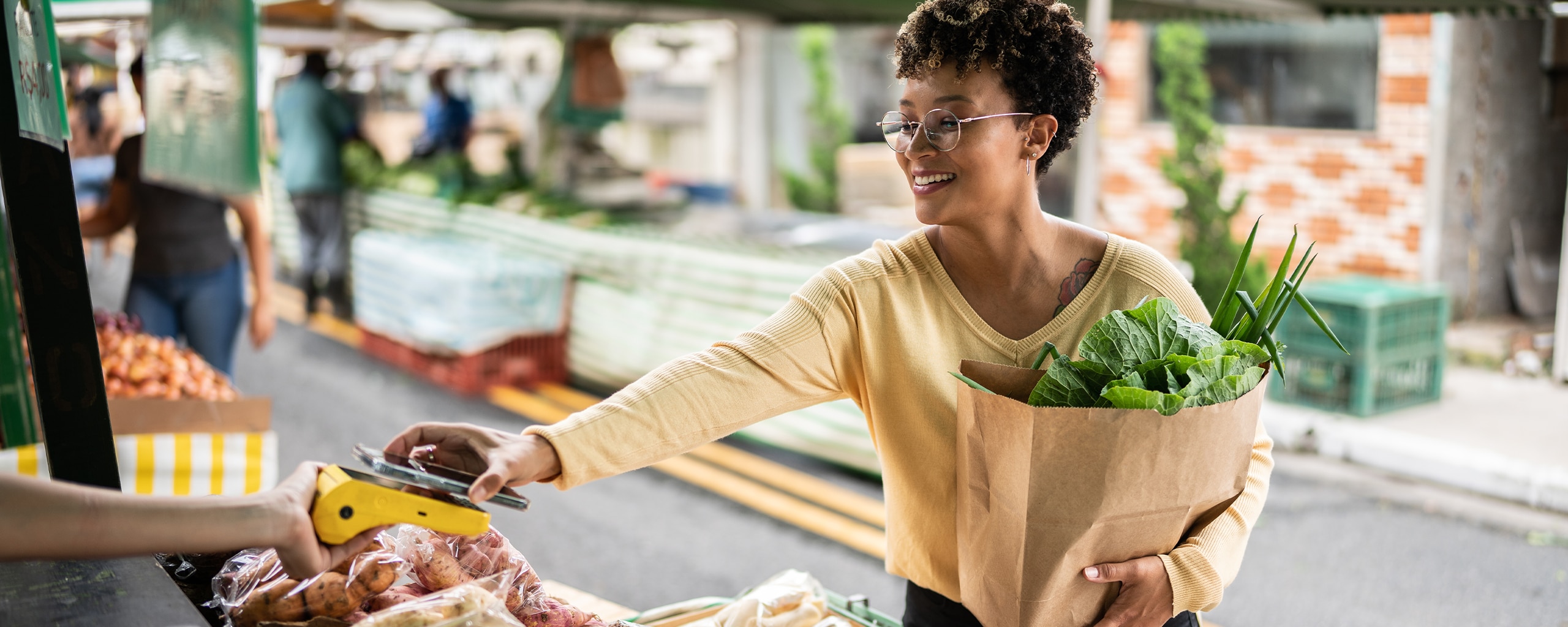 Person in glasses using contactless checkout to pay for groceries with a smartphone digital wallet.