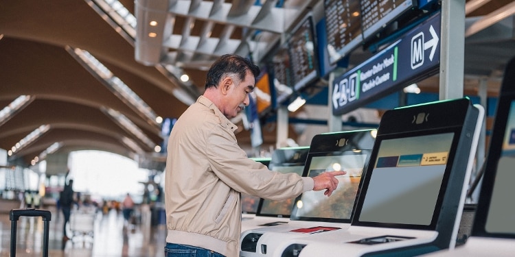 A photo of a person at an airport kiosk, printing out their airline boarding pass.